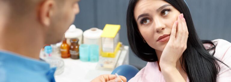 Root Canal - Woman holding jaw as if in pain.